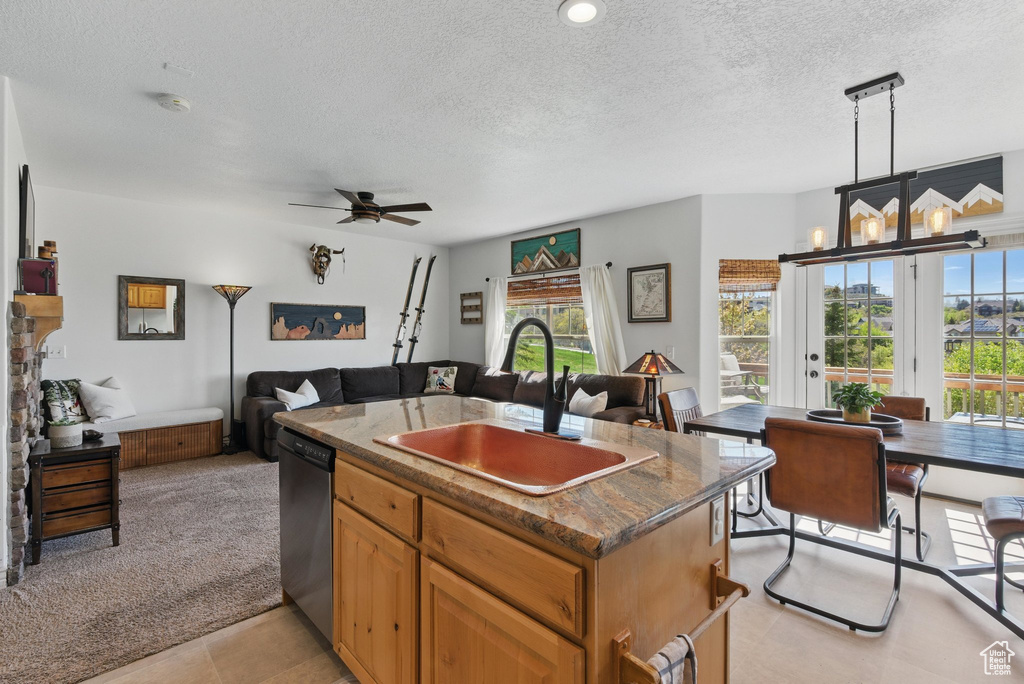 Kitchen with a sink, a textured ceiling, open floor plan, dishwasher, and a kitchen island with sink