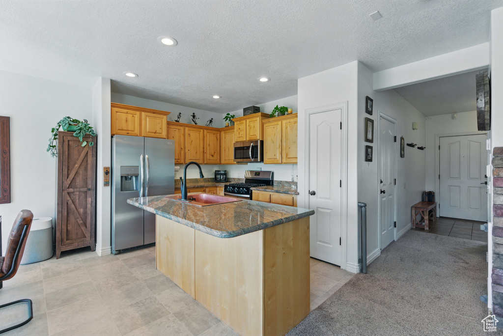 Kitchen featuring appliances with stainless steel finishes, a sink, dark stone counters, a center island with sink, and recessed lighting