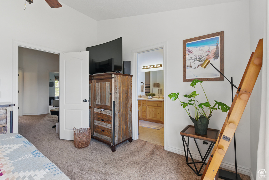 Bedroom featuring light colored carpet, lofted ceiling, ensuite bathroom, and baseboards
