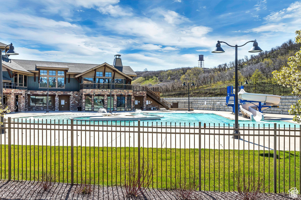 View of swimming pool featuring a water slide, stairway, and a patio area