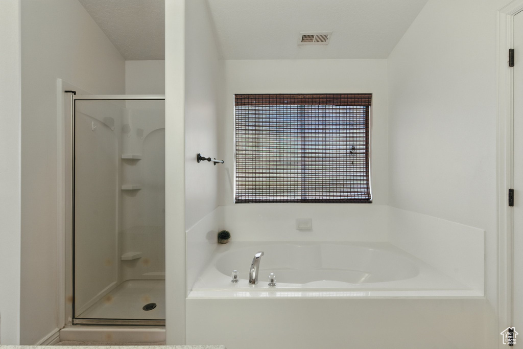 Bathroom featuring a stall shower and a bath