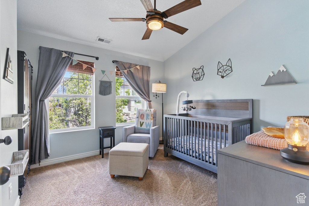Bedroom with carpet floors, lofted ceiling, baseboards, a nursery area, and a ceiling fan