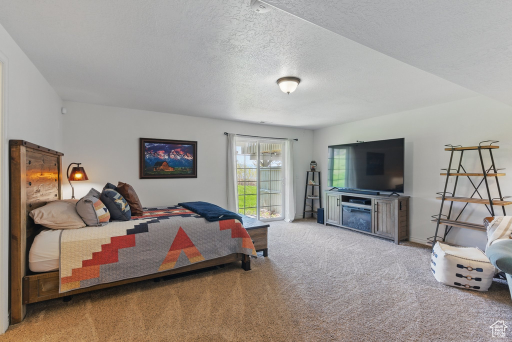Carpeted bedroom featuring a textured ceiling and a fireplace