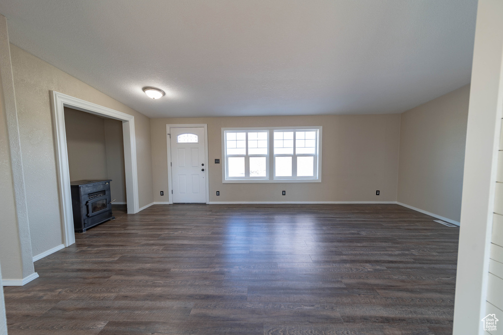 Entryway featuring a wood stove, dark wood-style flooring, and baseboards