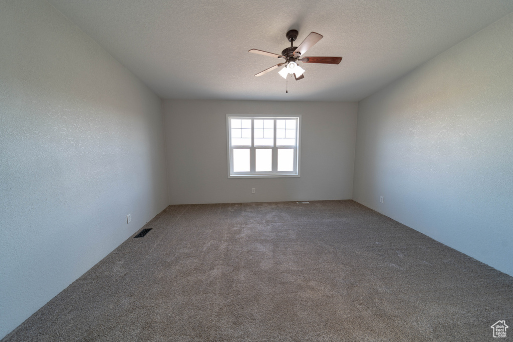 Carpeted spare room featuring ceiling fan