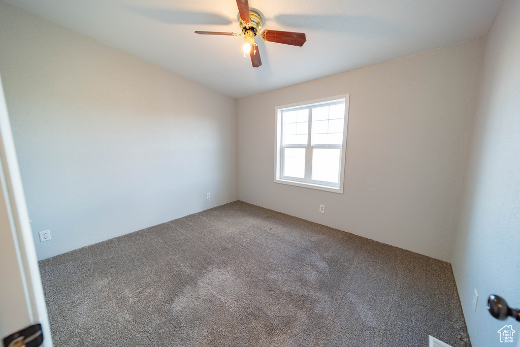 Carpeted empty room featuring a ceiling fan