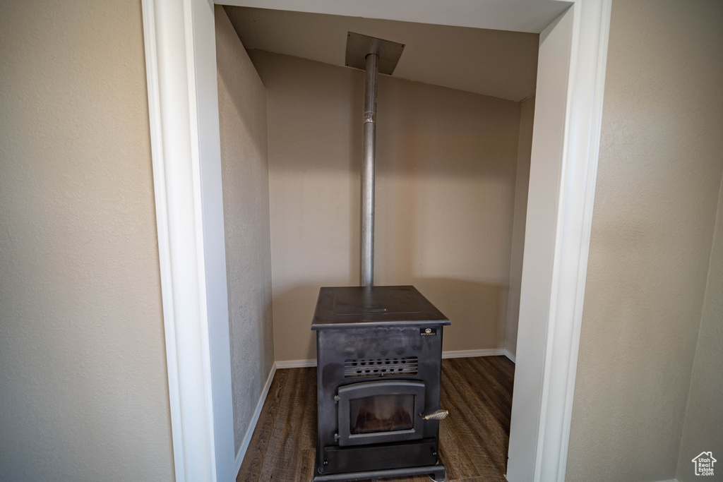 Detailed view of a wood stove, wood finished floors, and baseboards