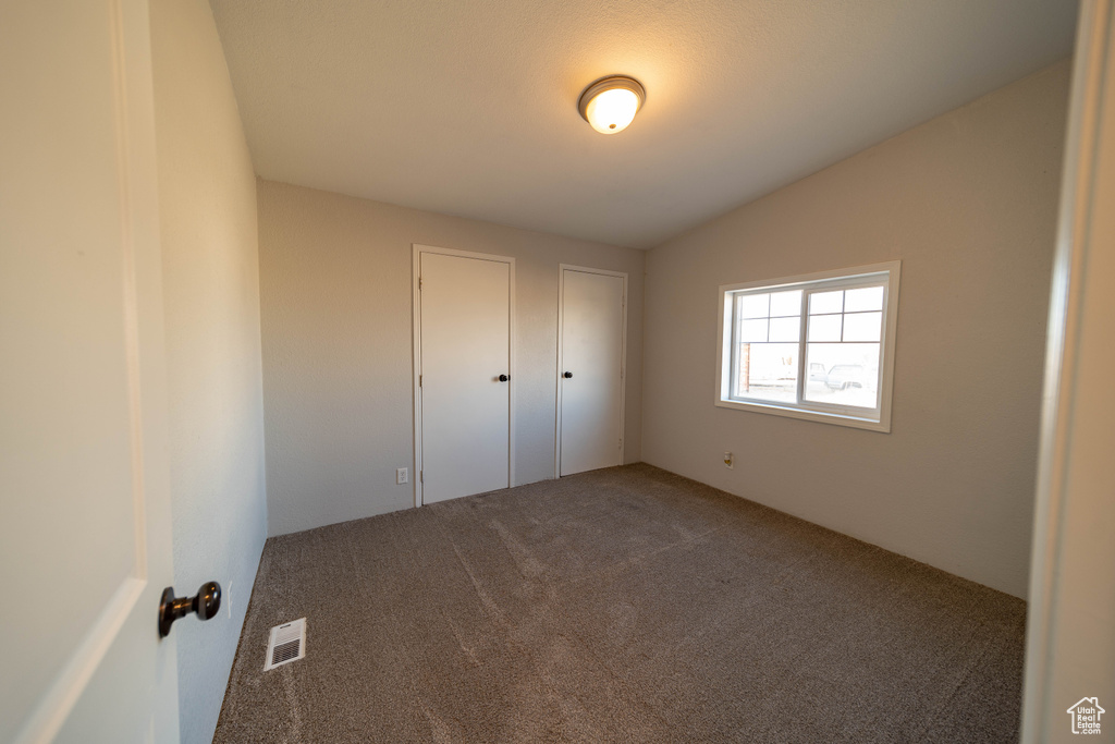 Unfurnished bedroom featuring carpet and lofted ceiling