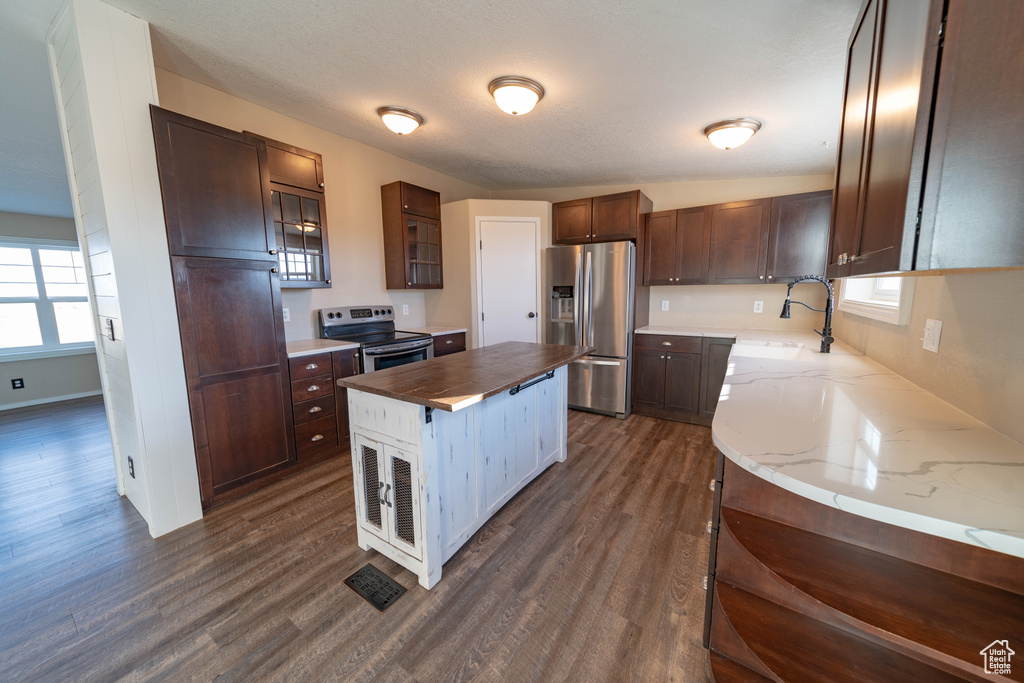 Kitchen featuring stainless steel appliances, dark wood-type flooring, a sink, butcher block counters, and a kitchen island
