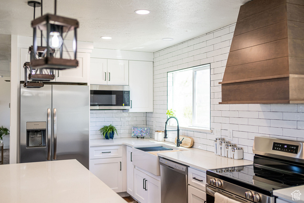 Kitchen featuring white cabinets, light countertops, appliances with stainless steel finishes, and tasteful backsplash