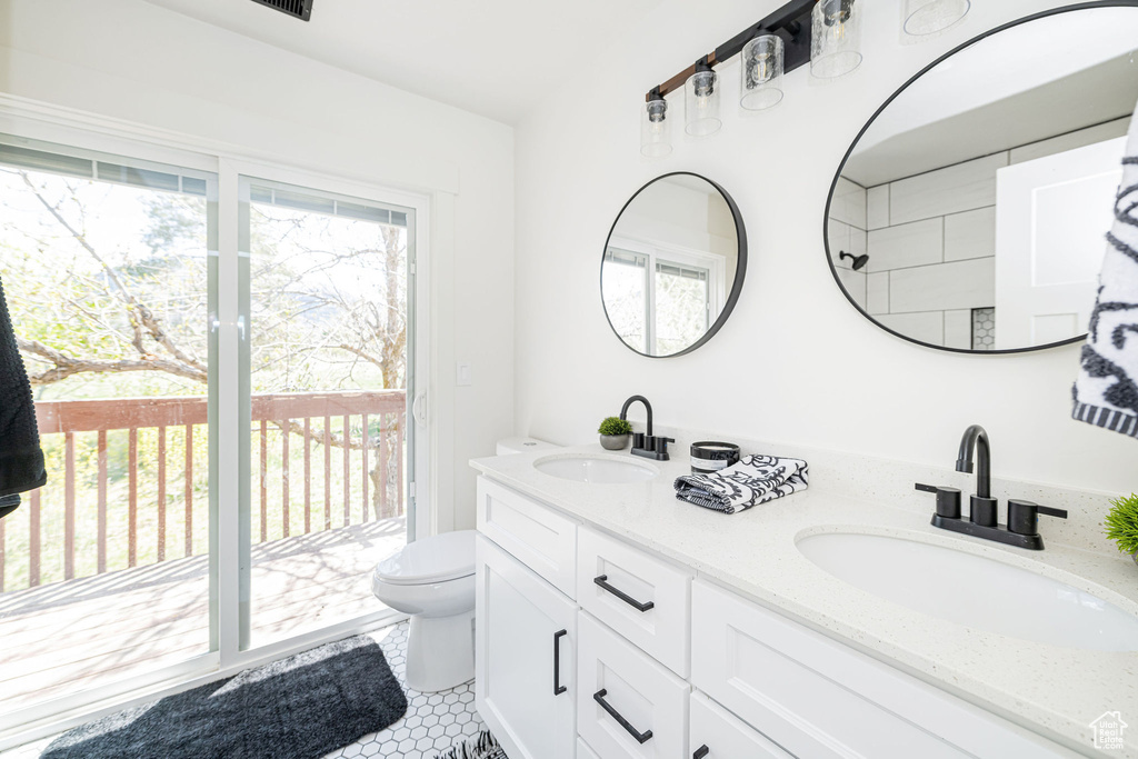 Bathroom featuring toilet, double vanity, and tile patterned floors