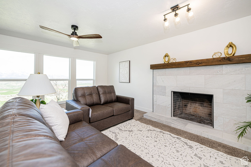 Living area featuring a tiled fireplace, carpet, ceiling fan, and baseboards