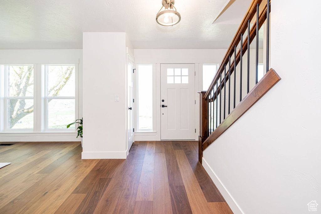 Foyer with baseboards, stairs, wood finished floors, and a wealth of natural light
