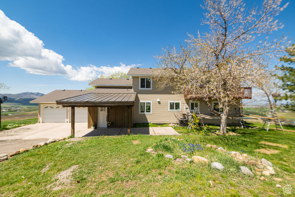 View of front of house with a garage, driveway, a front lawn, a mountain view, and a shingled roof