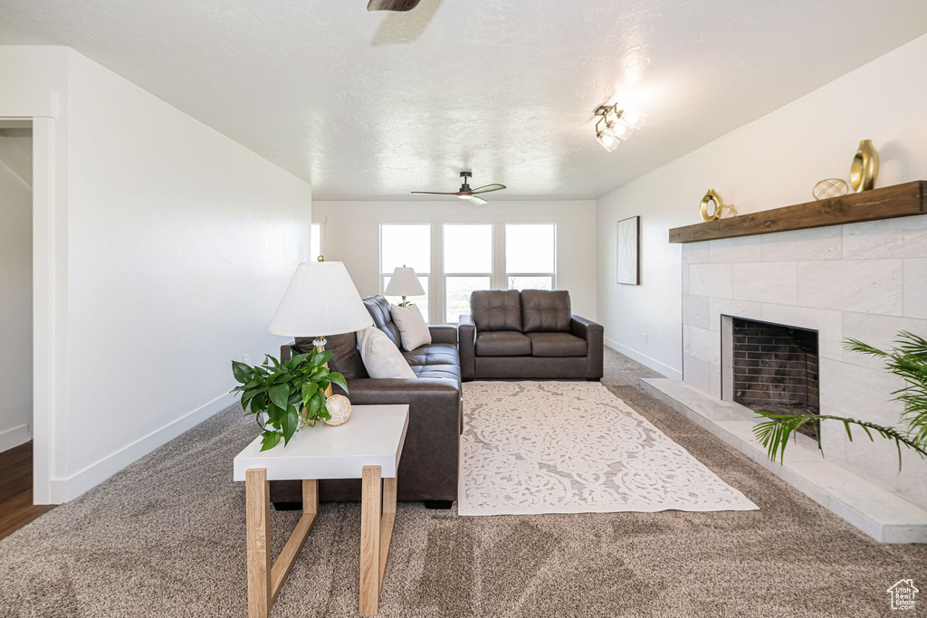 Living area with baseboards, carpet flooring, ceiling fan, and a tile fireplace