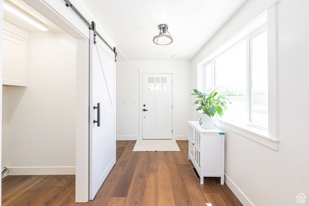 Entryway with baseboards, a barn door, and wood finished floors
