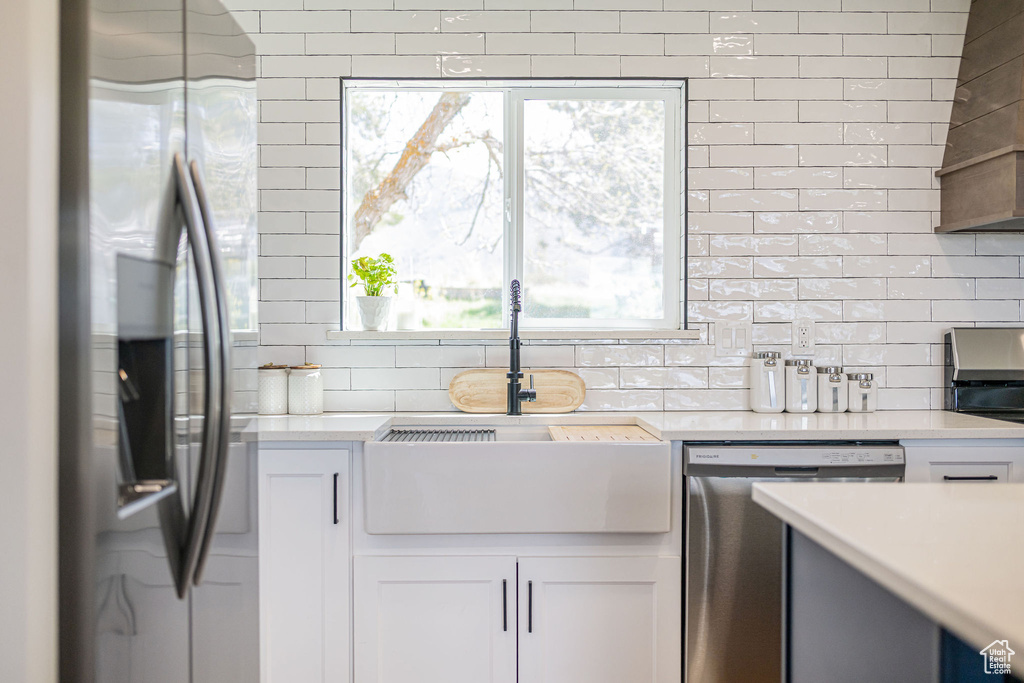 Kitchen with backsplash, appliances with stainless steel finishes, a sink, and light countertops