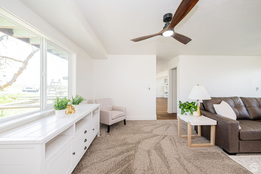Living room with baseboards, light carpet, and a ceiling fan