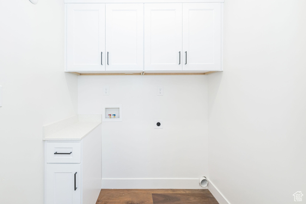Washroom featuring baseboards, hookup for a washing machine, dark wood-type flooring, electric dryer hookup, and cabinet space