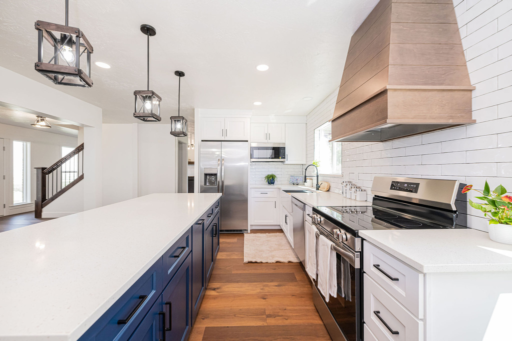 Kitchen featuring white cabinetry, custom range hood, a sink, light wood finished floors, and appliances with stainless steel finishes