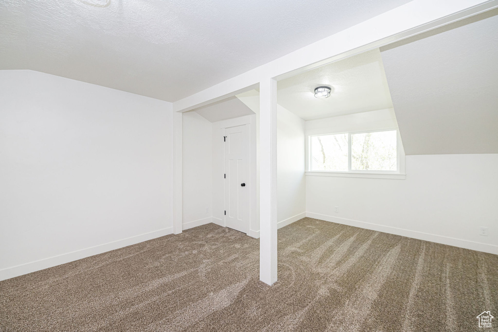 Bonus room featuring lofted ceiling, carpet floors, and baseboards