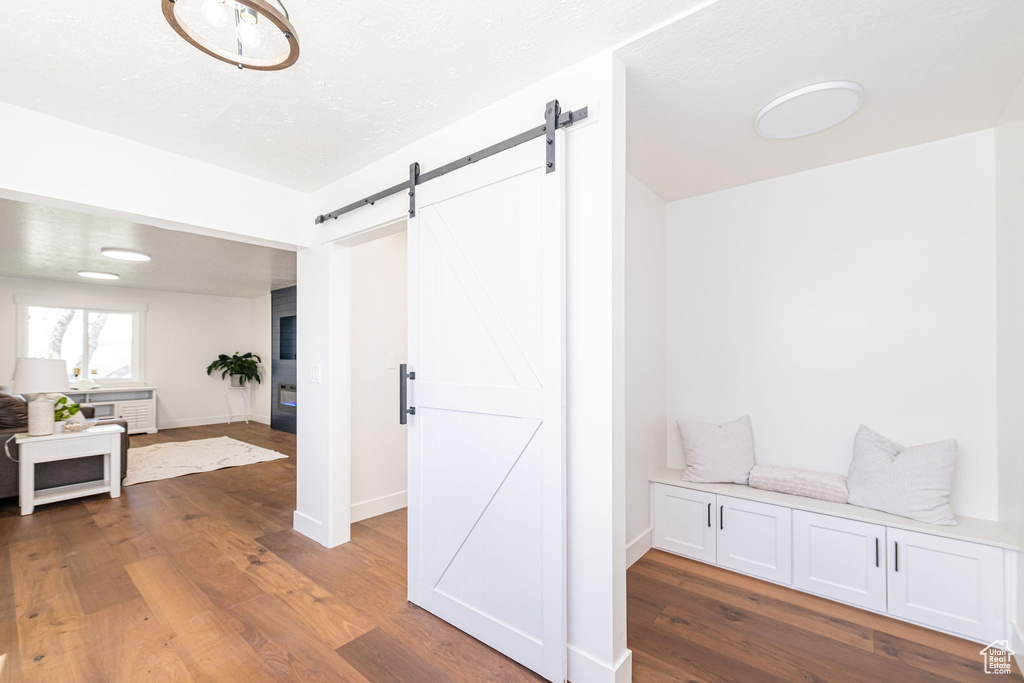 Interior space with baseboards, a barn door, and wood finished floors