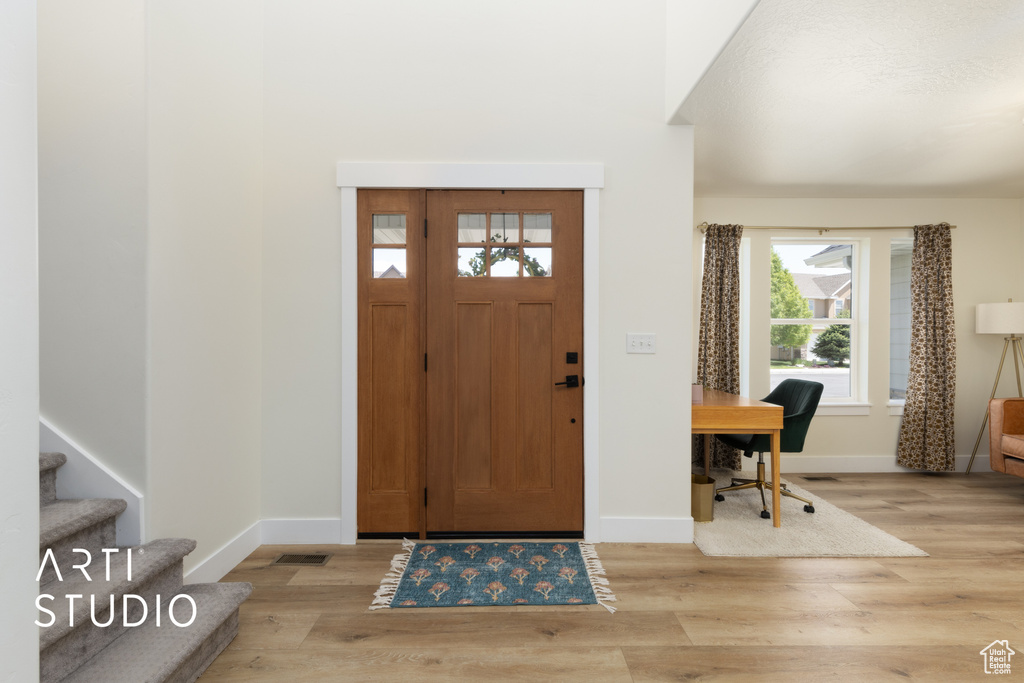Foyer with light wood-style floors, baseboards, and stairway