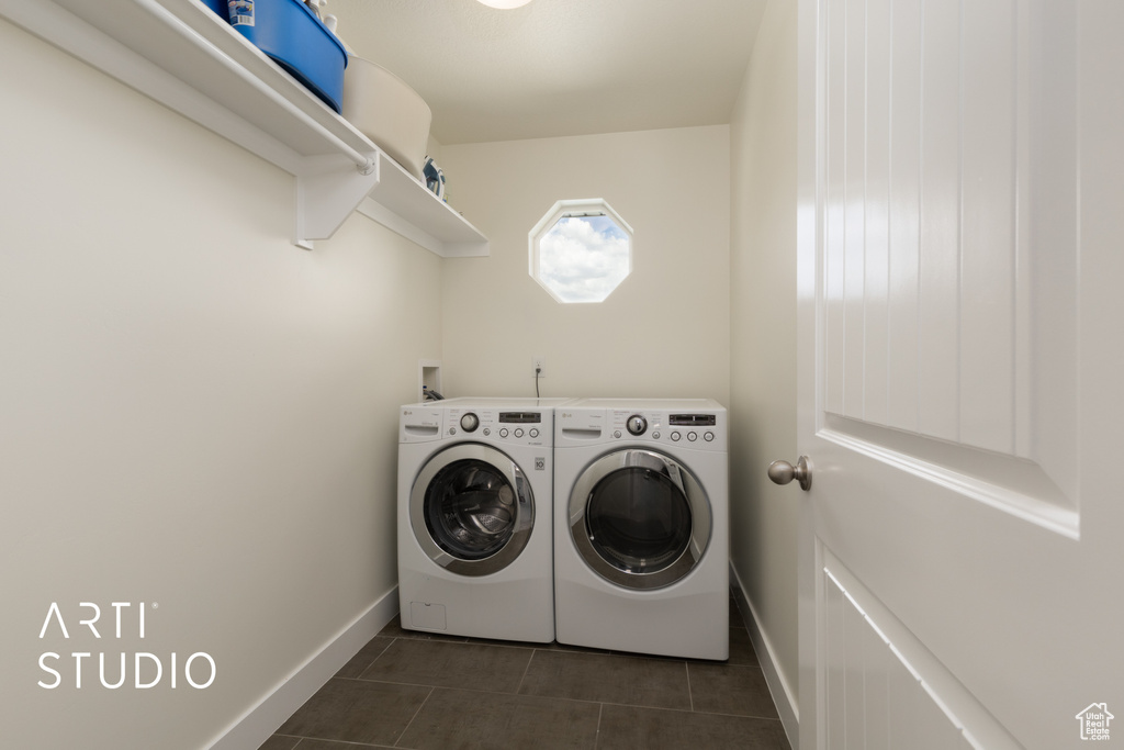 Laundry room with washing machine and clothes dryer, baseboards, and dark tile patterned floors