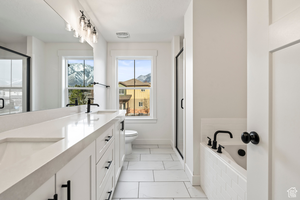 Full bath with marble look tiles, double vanity, baseboards, and a shower stall