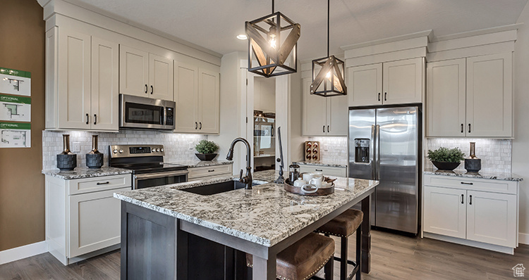 Kitchen featuring appliances with stainless steel finishes, a sink, decorative backsplash, dark wood finished floors, and light stone counters