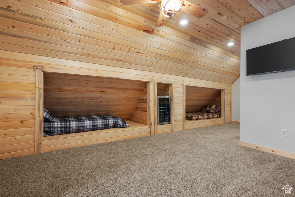 Unfurnished bedroom with wooden ceiling, carpet, lofted ceiling, wooden walls, and baseboards