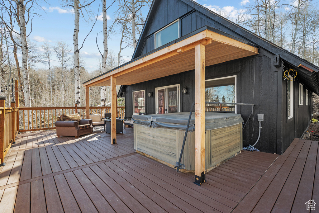 Wooden deck featuring a hot tub and an outdoor living space