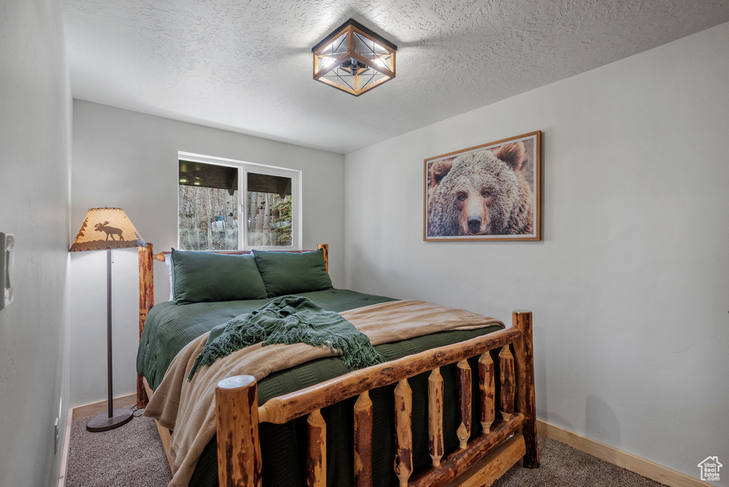 Bedroom featuring carpet floors, a textured ceiling, and baseboards