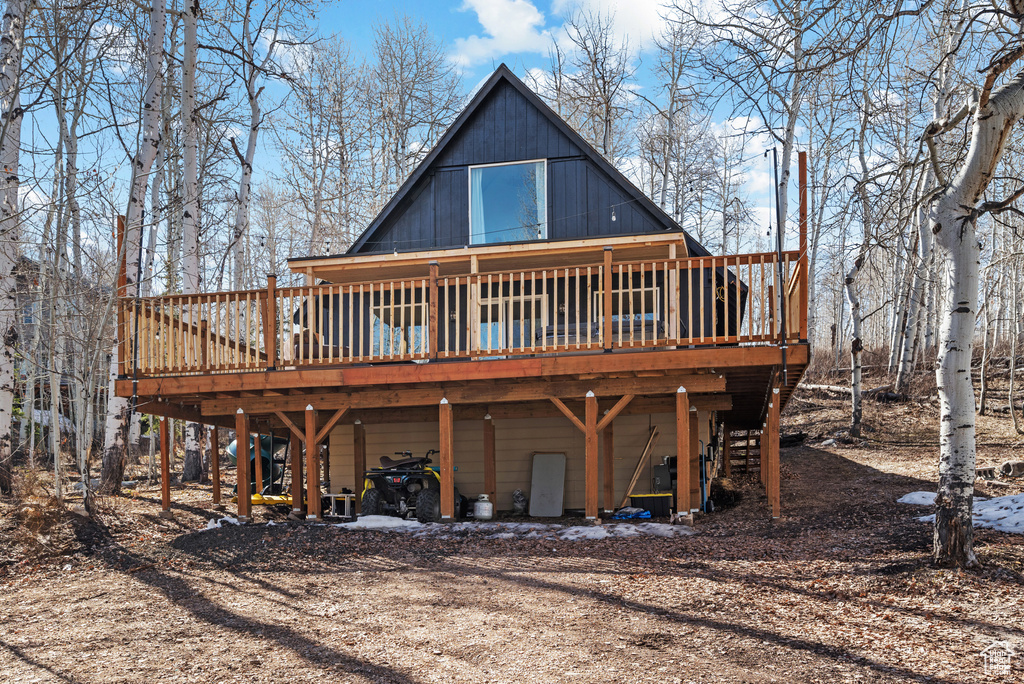 Back of property featuring a deck, a carport, and dirt driveway