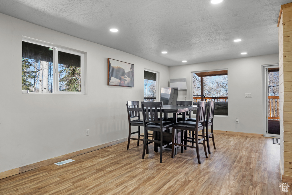 Dining area with recessed lighting, a textured ceiling, light wood-style flooring, and baseboards
