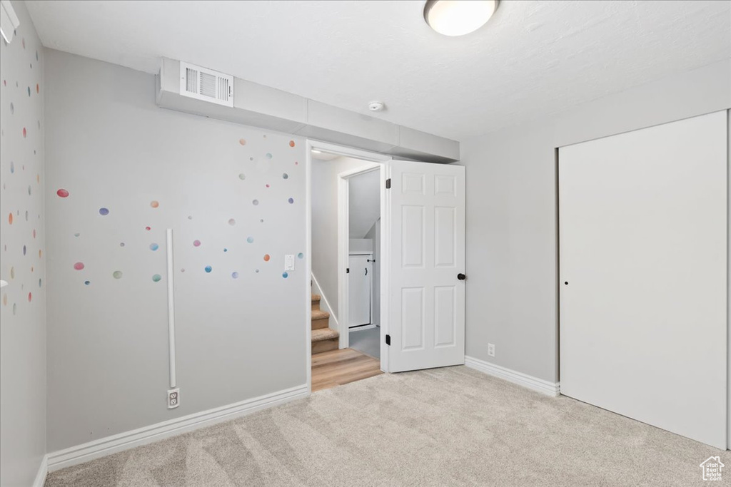 Unfurnished bedroom with light colored carpet, a closet, and baseboards