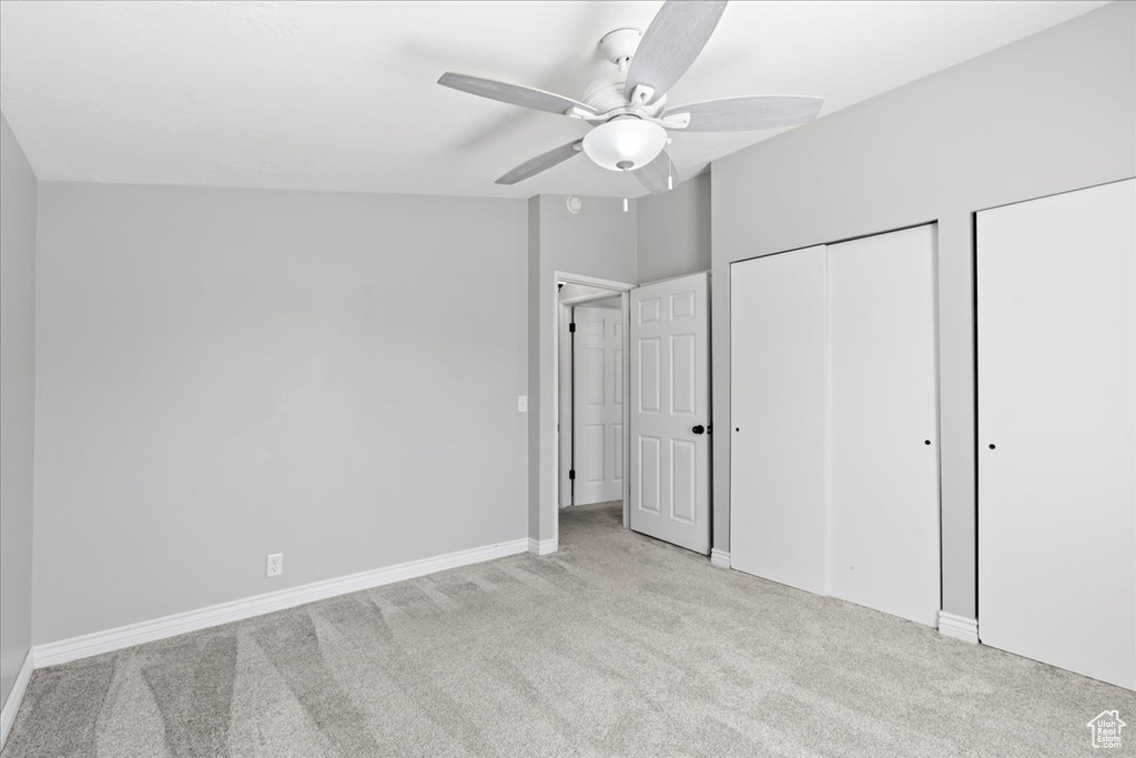 Unfurnished bedroom featuring carpet floors, multiple closets, baseboards, and ceiling fan