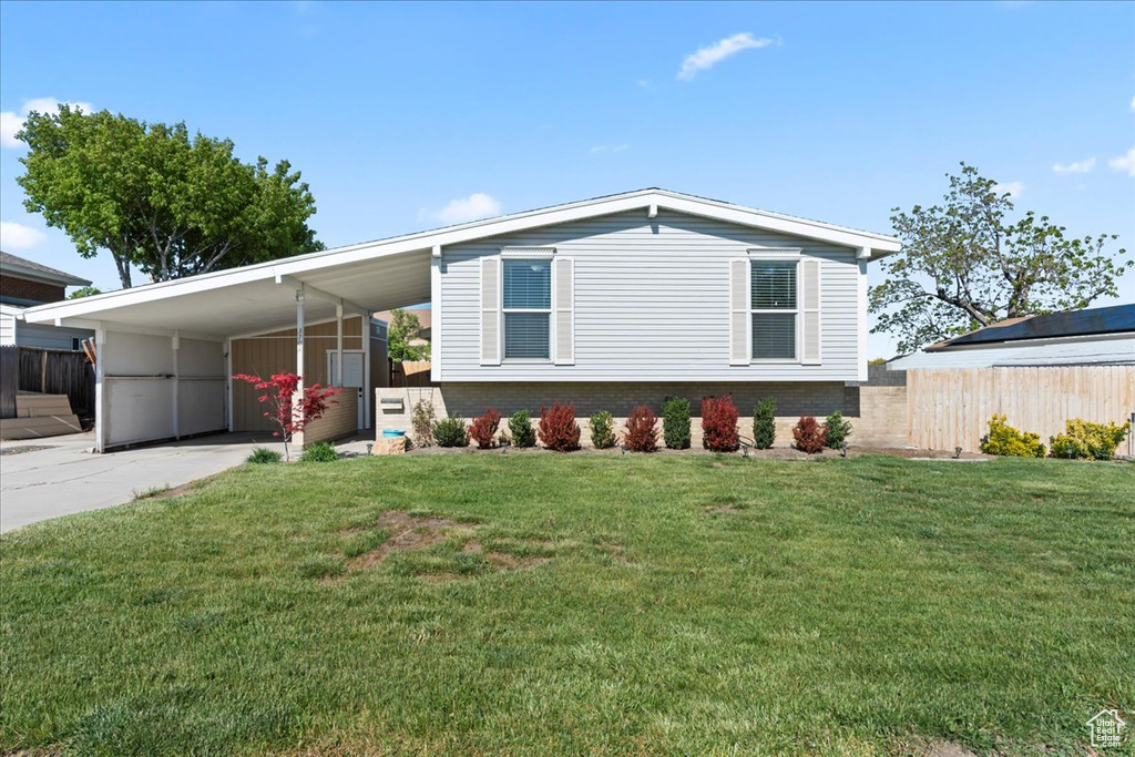 View of front of property featuring a carport, concrete driveway, and brick siding