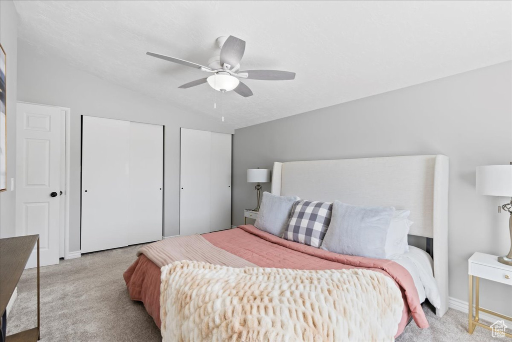 Bedroom featuring carpet, two closets, lofted ceiling, and ceiling fan