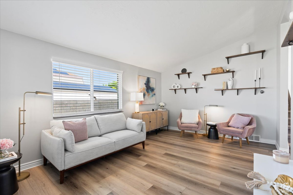 Living area featuring lofted ceiling, light wood-style flooring, and baseboards
