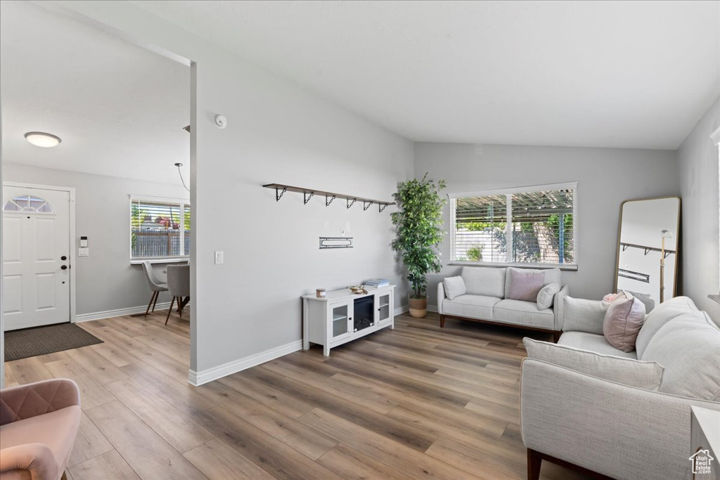 Living room with light wood-style flooring, vaulted ceiling, and baseboards