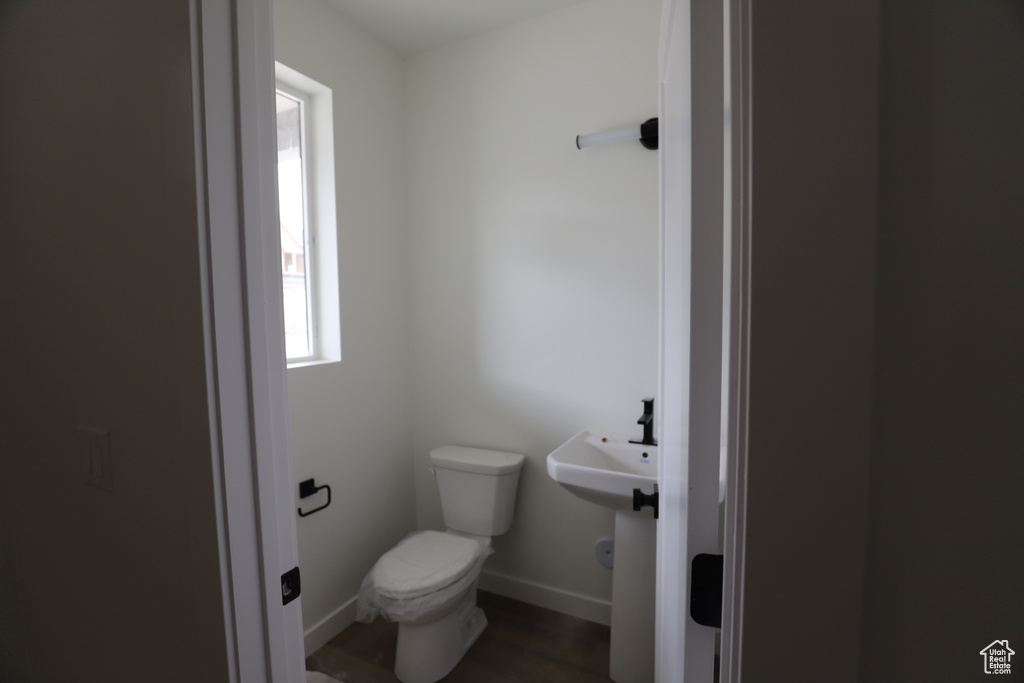 Bathroom with toilet, a sink, baseboards, and wood finished floors