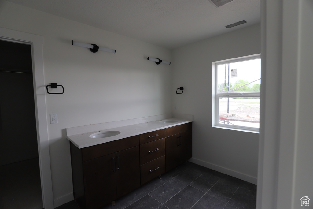 Bathroom with double vanity, baseboards, and tile patterned floors