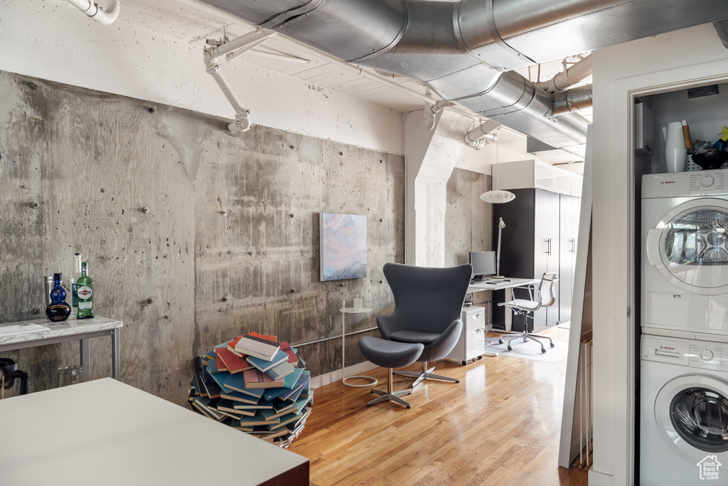 Basement featuring stacked washing machine and dryer, wood finished floors, and a desk
