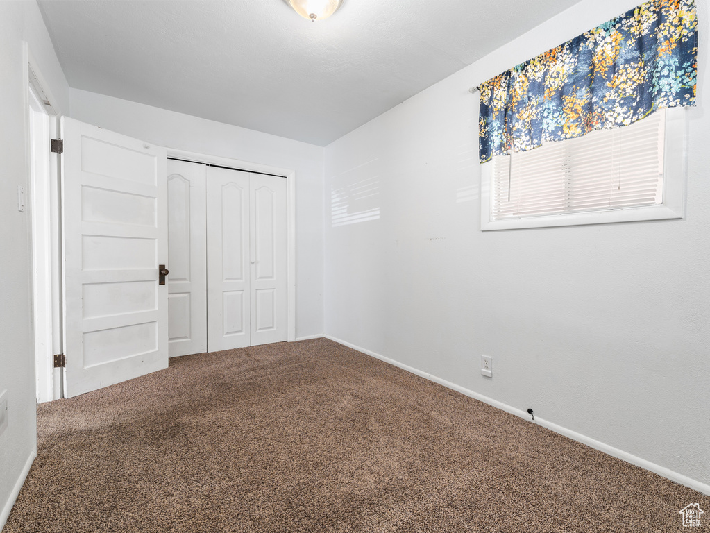 Unfurnished bedroom with carpet floors, a closet, and baseboards
