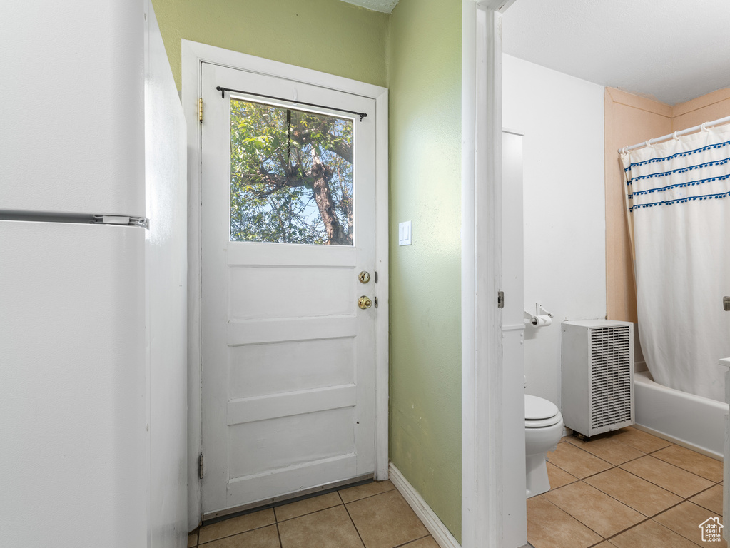 Entryway featuring light tile patterned floors, baseboards, and heating unit