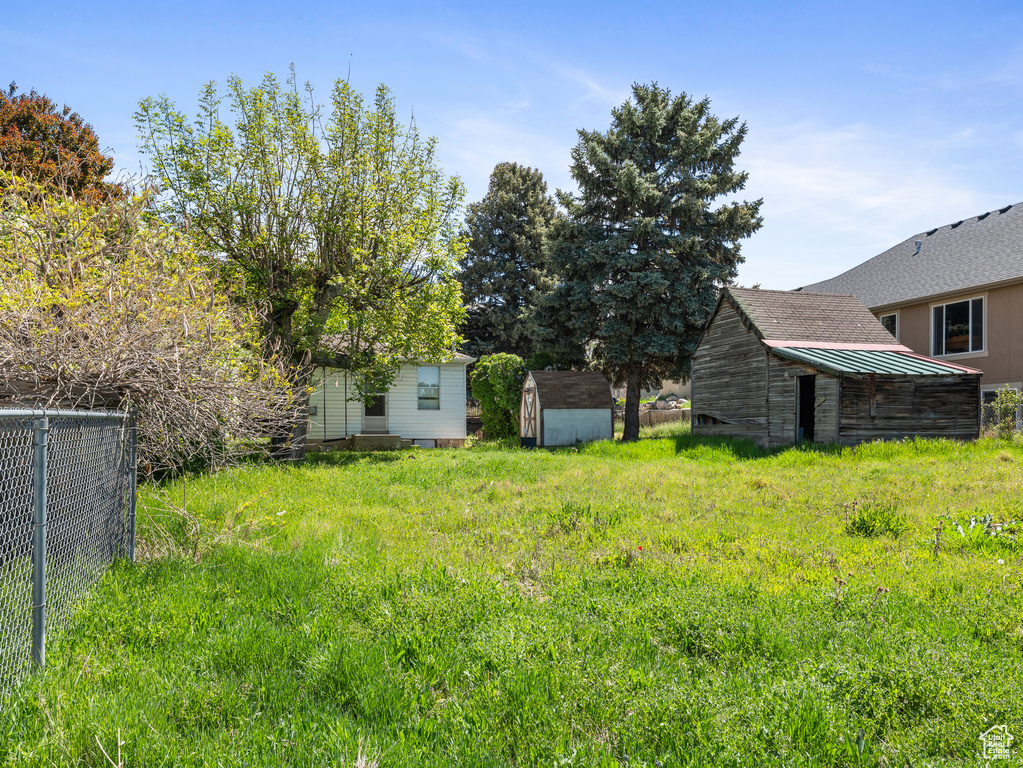 View of yard with a shed, fence, and an outbuilding