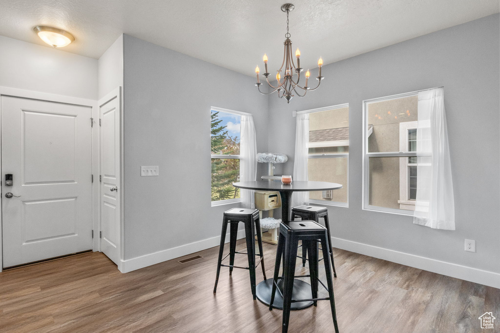 Dining area with a chandelier, wood finished floors, and baseboards