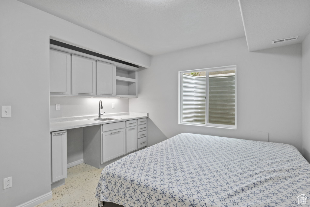 Bedroom featuring a sink, dark aggregate flooring, and baseboards
