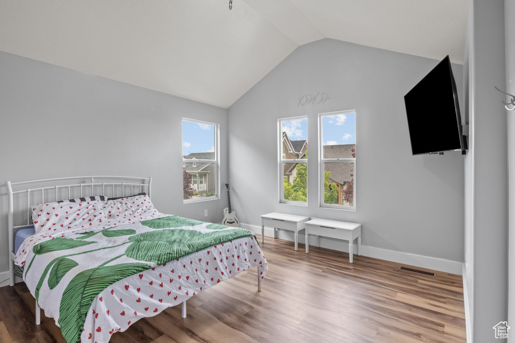 Bedroom with lofted ceiling, wood finished floors, and baseboards